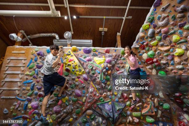 asiatische athleten klettern im boulderstudio auf die wand - blick in die kamera - only japanese stock-fotos und bilder