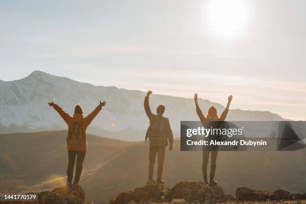 happy group of people tourists with backpacks with raised hands in the mountains. the concept of travel and freedom. - arms raised sunrise stock pictures, royalty-free photos & images