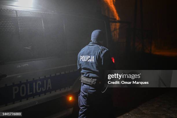 Police officer walks towards a check point as permitted cars are allowed to cross into the crime scene on November 16, 2022 in Przewodow, Poland....