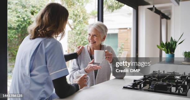 sanità, infermiera senior e donna anziana con caffè mattutino in cucina con un sorriso. impiegata medica, donne e persone felici in una casa di riposo che parlano insieme con felicità - woman smile kitchen foto e immagini stock