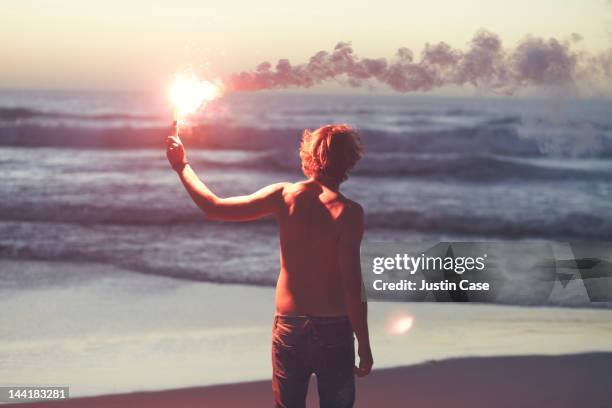 man with a burning flare in his hands by the ocean - schiffbrüchiger stock-fotos und bilder