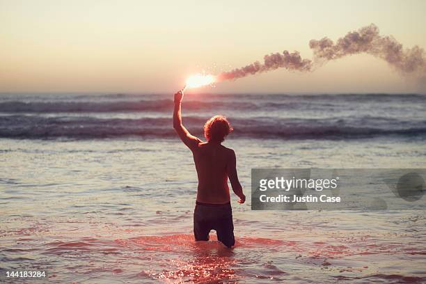 man standing in the ocean with burning flare - distress flare stock pictures, royalty-free photos & images