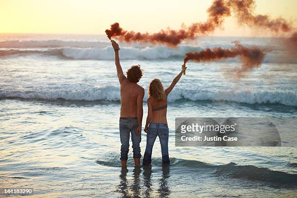 couple standing in the ocean with smoke grenades - the castaway ストックフォトと画像