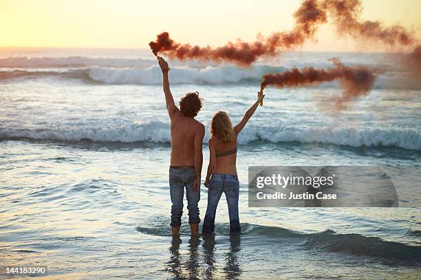 couple standing in the ocean with smoke grenades - distress flare stock pictures, royalty-free photos & images