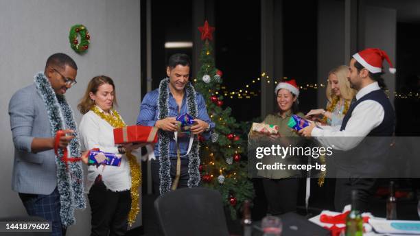 group of multiracial business people celebrating christmas and opening christmas presents at office - gift exchange stock pictures, royalty-free photos & images