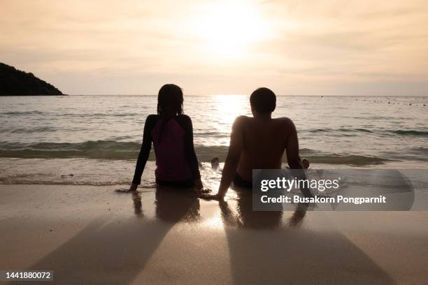 couple watching the sunrise on a beach on vacation. - japanese couple beach stock pictures, royalty-free photos & images