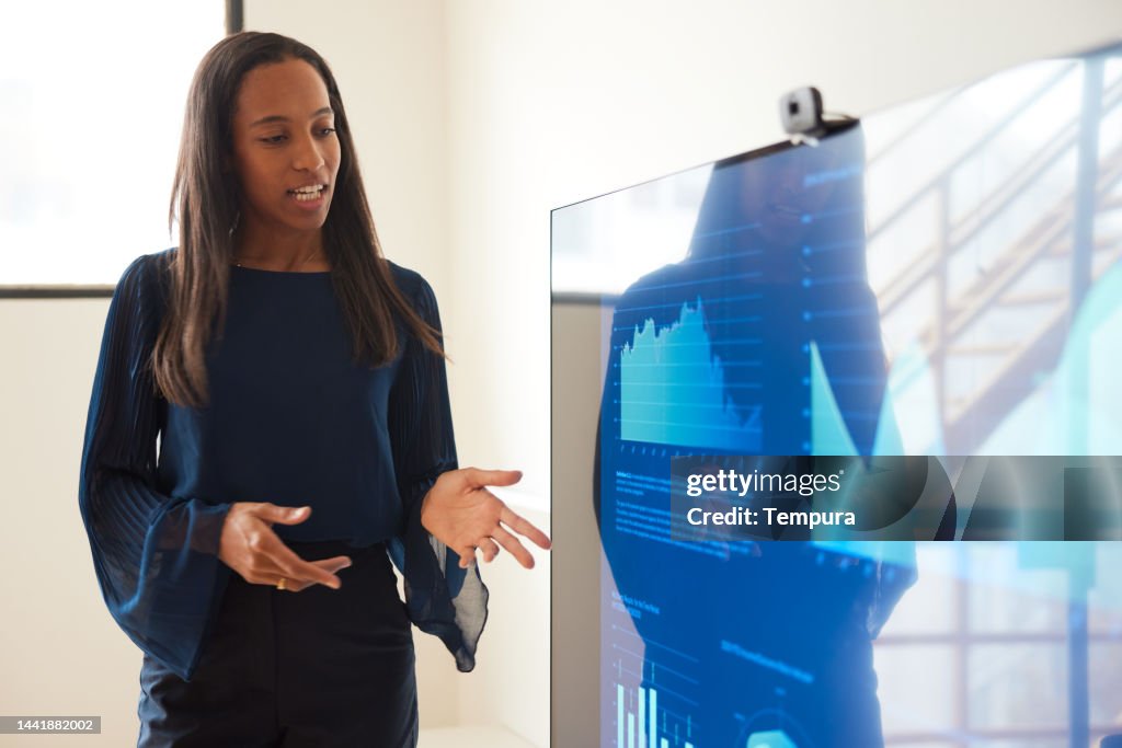 Große attraktive schwarze Geschäftsfrau vermittelt Informationen bei Geschäftspräsentation