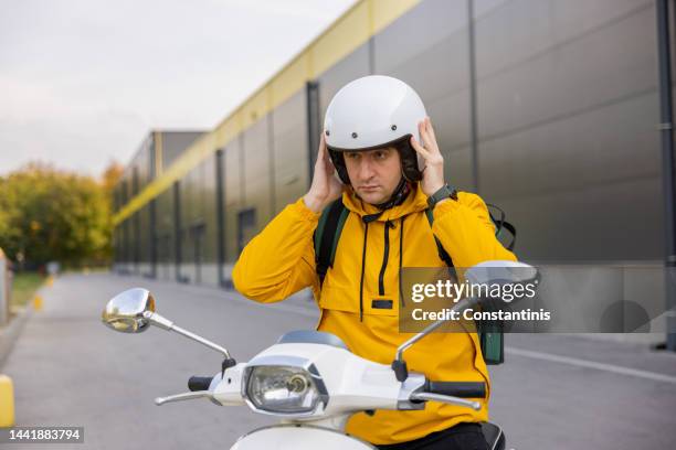 クラッシュヘルメットを調整するスクーターの配達員 - adjusting ストックフォトと画像