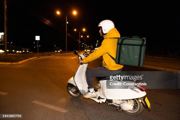 delivery person driving scooter through city in the night - riding vespa stock pictures, royalty-free photos & images