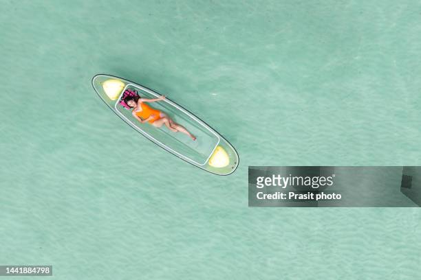 asian woman enjoying her vacation on glass bottom kayak in tropical ocean at phuket, thailand - bateau à rames photos et images de collection