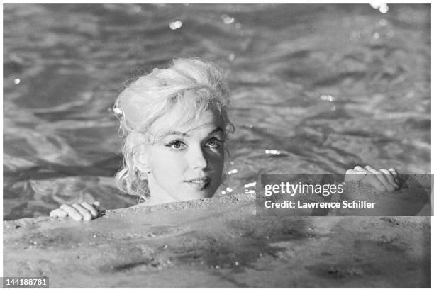 In the water, American actress Marilyn Monroe looks over the edge of a pool for a scene during the filming of 'Something's Got to Give' , Los...