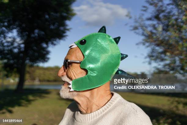 elderly man portrait with dinosaur mask - bizarre stock pictures, royalty-free photos & images