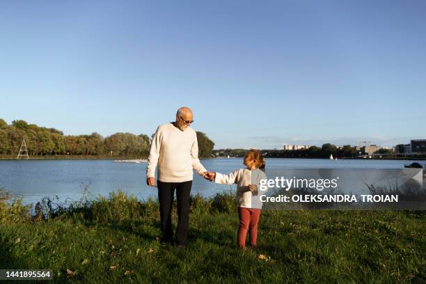 grey haired grandfather with child girl near lake on nature - poznan poland stock pictures, royalty-free photos & images