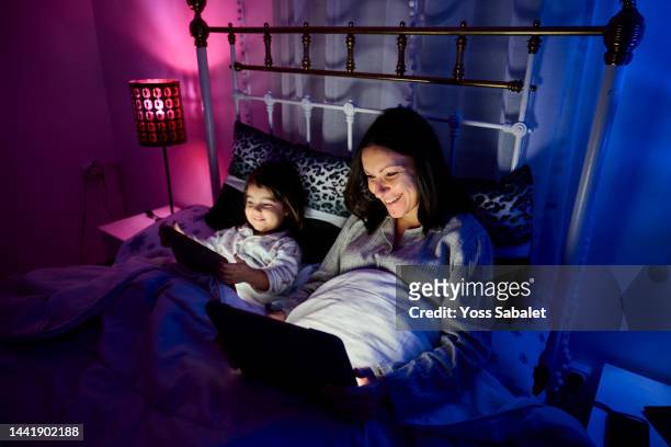 mother and daughter in bed happy with tablet - film screening room stock pictures, royalty-free photos & images