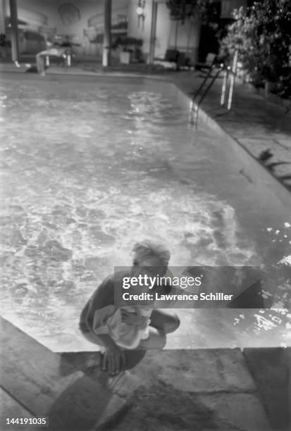 American actress Marilyn Monroe holds a towel in front of her as she climbs, topless, out of a pool during the filming of 'Something's Got to Give' ,...