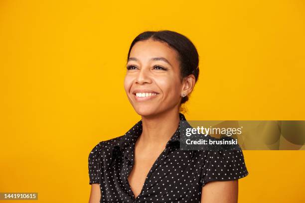 retrato de estudio en primer plano de una alegre mujer afroamericana de mediana edad con blusa de lunares sobre un fondo amarillo - black blouse fotografías e imágenes de stock