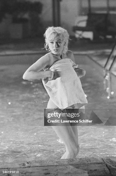 American actress Marilyn Monroe holds a towel in front of her as she stands, topless, in a pool during the filming of 'Something's Got to Give' , Los...