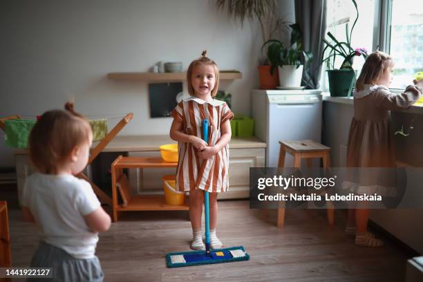 girl child with mop washes floor in kindergarten. montessori practical life zone. help around house. kids clean up together. - bad kids classroom stockfoto's en -beelden