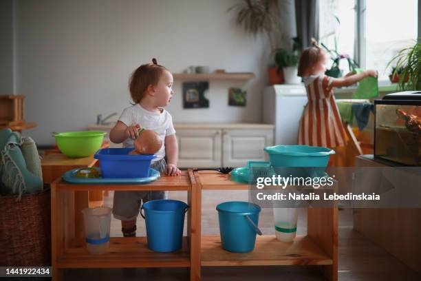 toddler boy washing doll in basin in practical life area in kindergarten. exercises from practical life according to montessori method. - bad kids classroom stockfoto's en -beelden