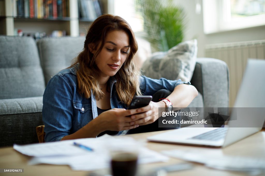 Using Phone While Study Young Smiling Woman Using Mobile Phone While Studying At Home High-Res ...