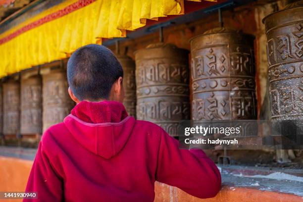 novice tibetan monk turning the prayer wheels, tsarang village, upper mustang, nepal - nepal child stock pictures, royalty-free photos & images