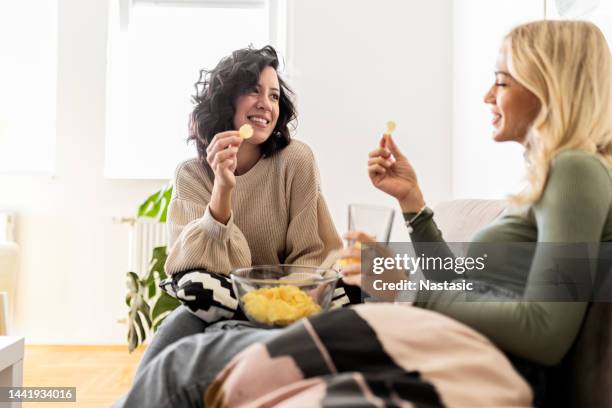 girlfriend sitting on sofa eating unhealthy - potato chip stock pictures, royalty-free photos & images