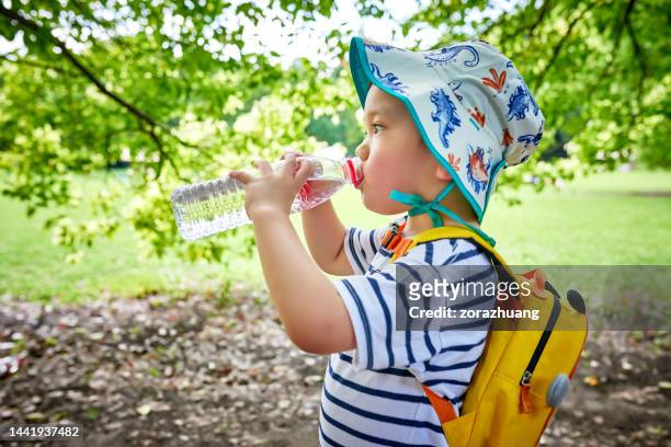 close-up of little boy drinking water under tree - boy drinking water stock pictures, royalty-free photos & images
