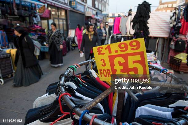 Boards advertise multi deals on Items of low priced clothing on a clothing stall in Barking Town Centre street market on November 14, 2022 in...