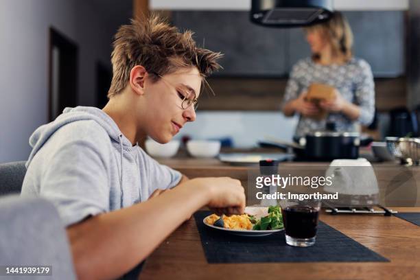 teenager mit rührei zum frühstück - mutter kind brot glücklich stock-fotos und bilder