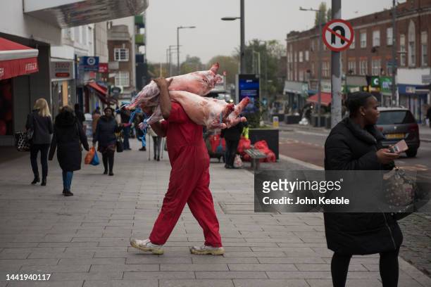 Butcher carries animal carcasses into a Halal butchers shop on the Heathway on November 14, 2022 in Dagenham, London.