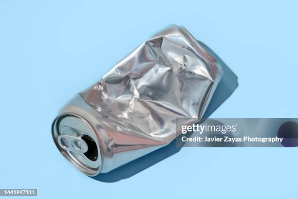 crumpled aluminum can on blue background - verpletterd stockfoto's en -beelden