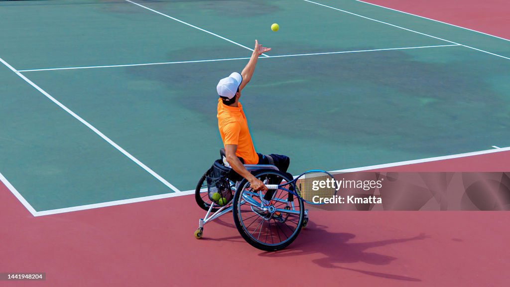 Wheelchair tennis player preparing to serve during a wheelchair tennis match.