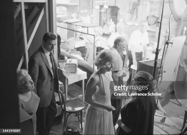 As French actor Yves Montand waits, his co-star American actress Marilyn Monroe talks with her dialogue coach Paula Strasberg during the filming of...