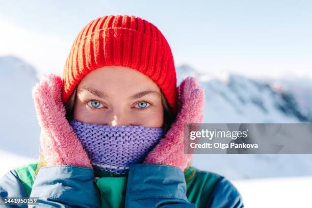 smiling woman with face covered with scarf into the mountains in winter - cappello di lana foto e immagini stock