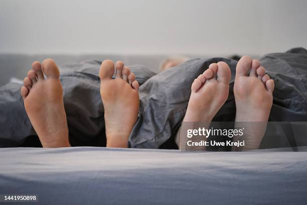 feet of couple in bed - romantic young couple sleeping in bed stock pictures, royalty-free photos & images