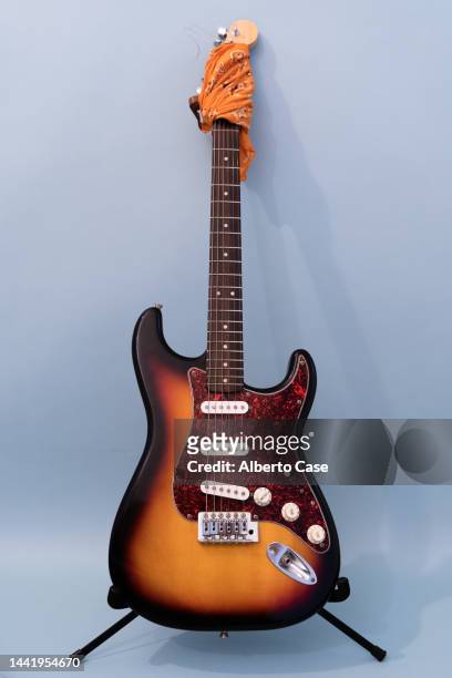 reddish, orange and black electric guitar on a blue background - electric guitar foto e immagini stock
