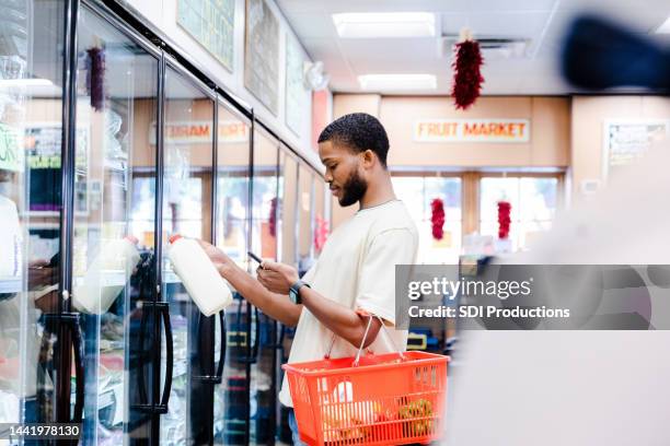 young adult male reads a message - man in grocery store stock pictures, royalty-free photos & images