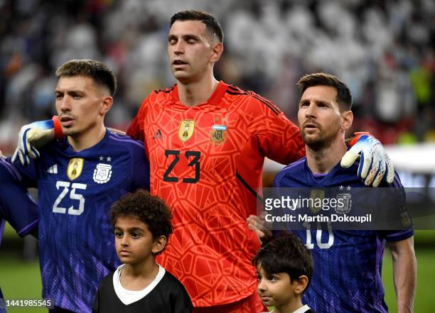 Lisandro Martínez, Damian Emiliano "Dibu" Martinez and Lionel Messi looks on as they listen to the national anthem during the international friendly...