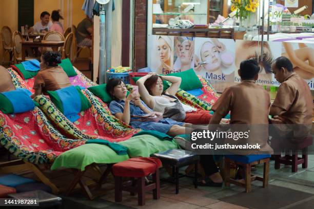 some tourists are getting thai foot massage in khao san road. - khao san road stock pictures, royalty-free photos & images