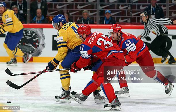 Alexander Perezhogin and Yevgeni Biryuko of Russia and Henrik Zetterberg of Sweden battle for the puck during the IIHF World Championship group S...