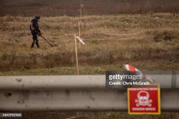 Member of a demining team works to clear mines and unexploded ordnance from the side of the main road leading to Kherson City on November 16, 2022 in...