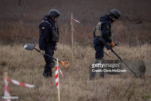 Members of a demining team work to clear mines and unexploded ordinance from the side of the main road leading to Kherson City on November 16, 2022...