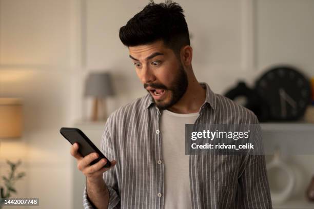 l’homme tenant le smartphone lire des sms désagréables se sent stressé - affolé photos et images de collection