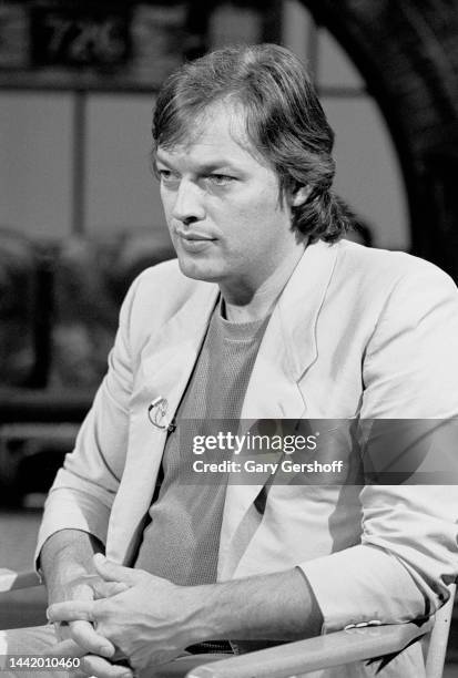 View of the English Rock musician David Gilmour, of the band Pink Floyd, as he sits in a director's chair during an interview on MTV at Teletronic...