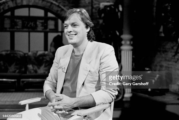 View of the English Rock musician David Gilmour, of the band Pink Floyd, as he sits in a director's chair during an interview on MTV at Teletronic...