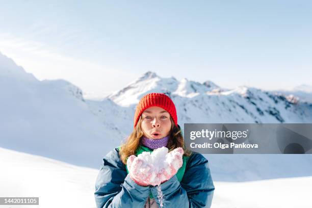 woman blows on the snow at a ski resort - schnee pusten stock-fotos und bilder