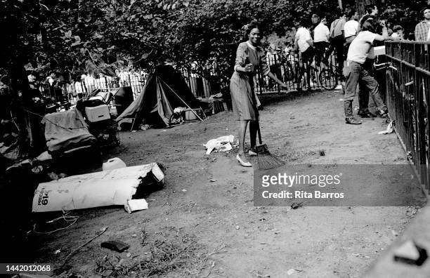 An attendee uses a broom to sweep the ground around an encampment in Tompkins Square Park during Wigstock, an annual drag festival New York, New...