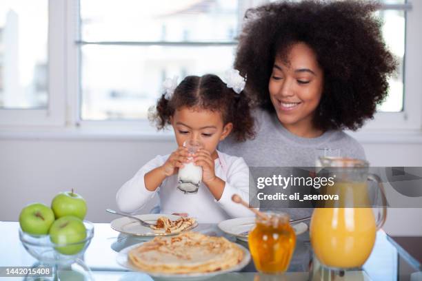 jeune mère et fille afro-américaines ayant le petit déjeuner - kids play apple photos et images de collection