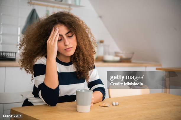 portrait of a young woman sitting miserable at home due to some health problems - failure stock pictures, royalty-free photos & images