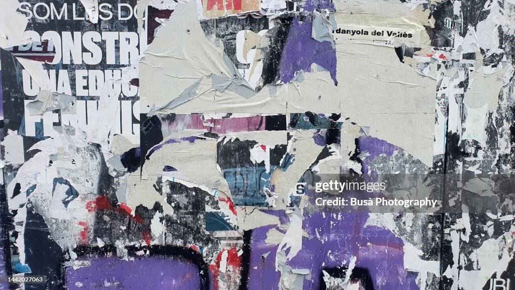 Scratched layers of posters and placards on a street wall